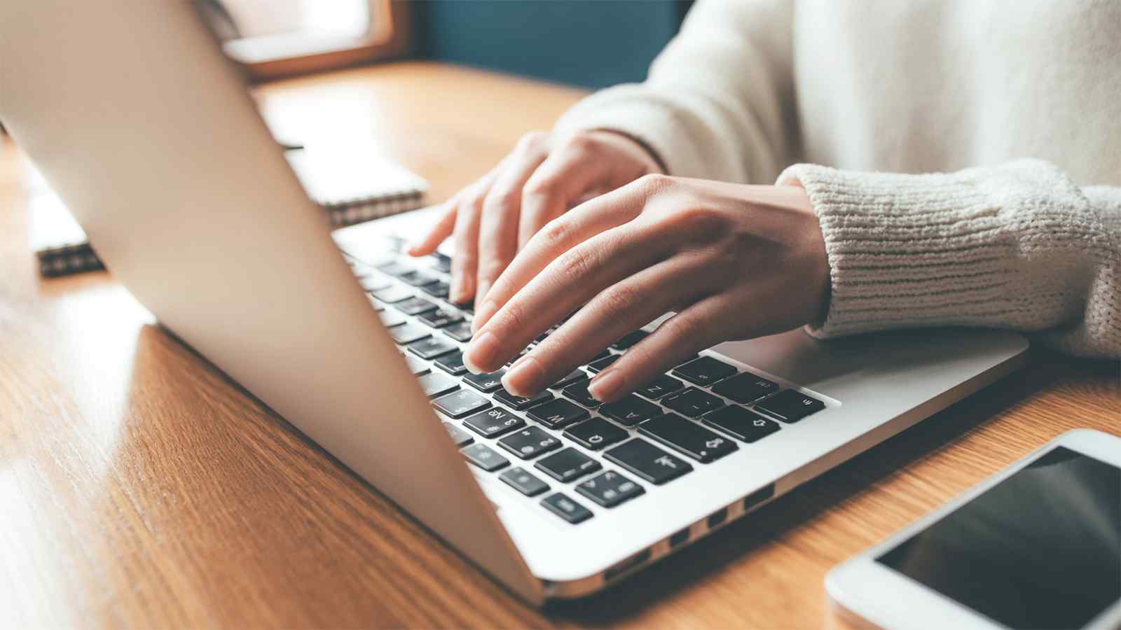Close-up of female hands typing on a laptop, utilizing advanced features of Google My Business for business optimization.
