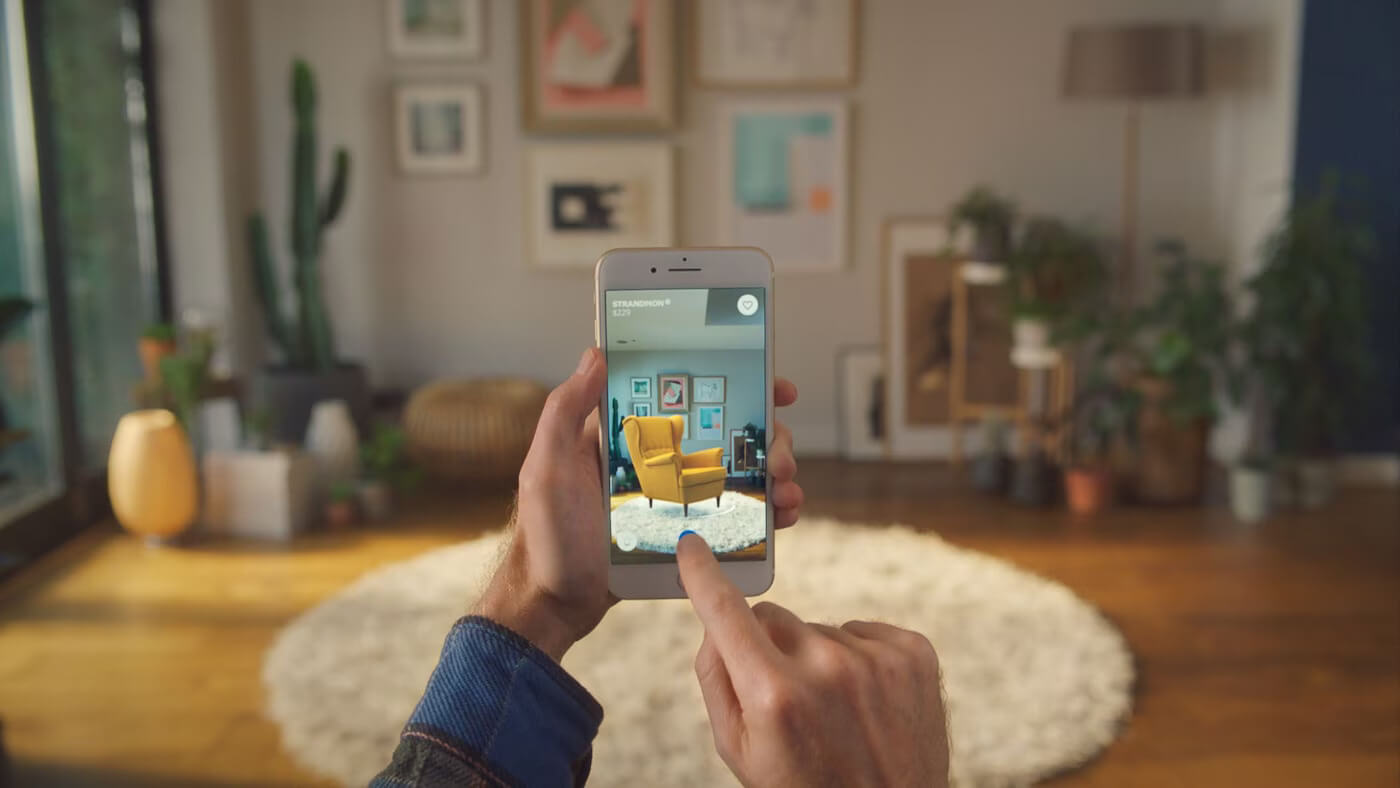 Man using IKEA Place app to visualize an AR chair in his living room.
