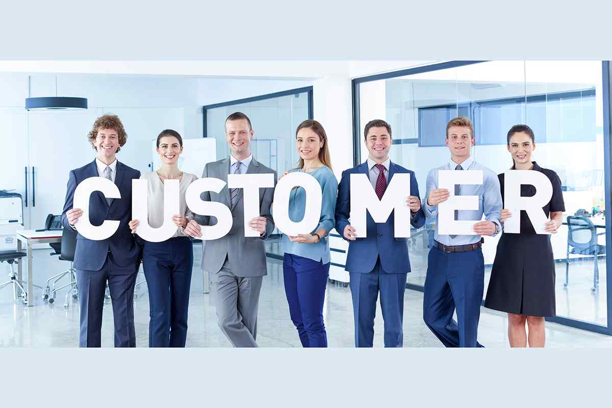 Male and female business people in an office holding letters that spell out the word "Customer," emphasizing the importance of customer-centricity and focus