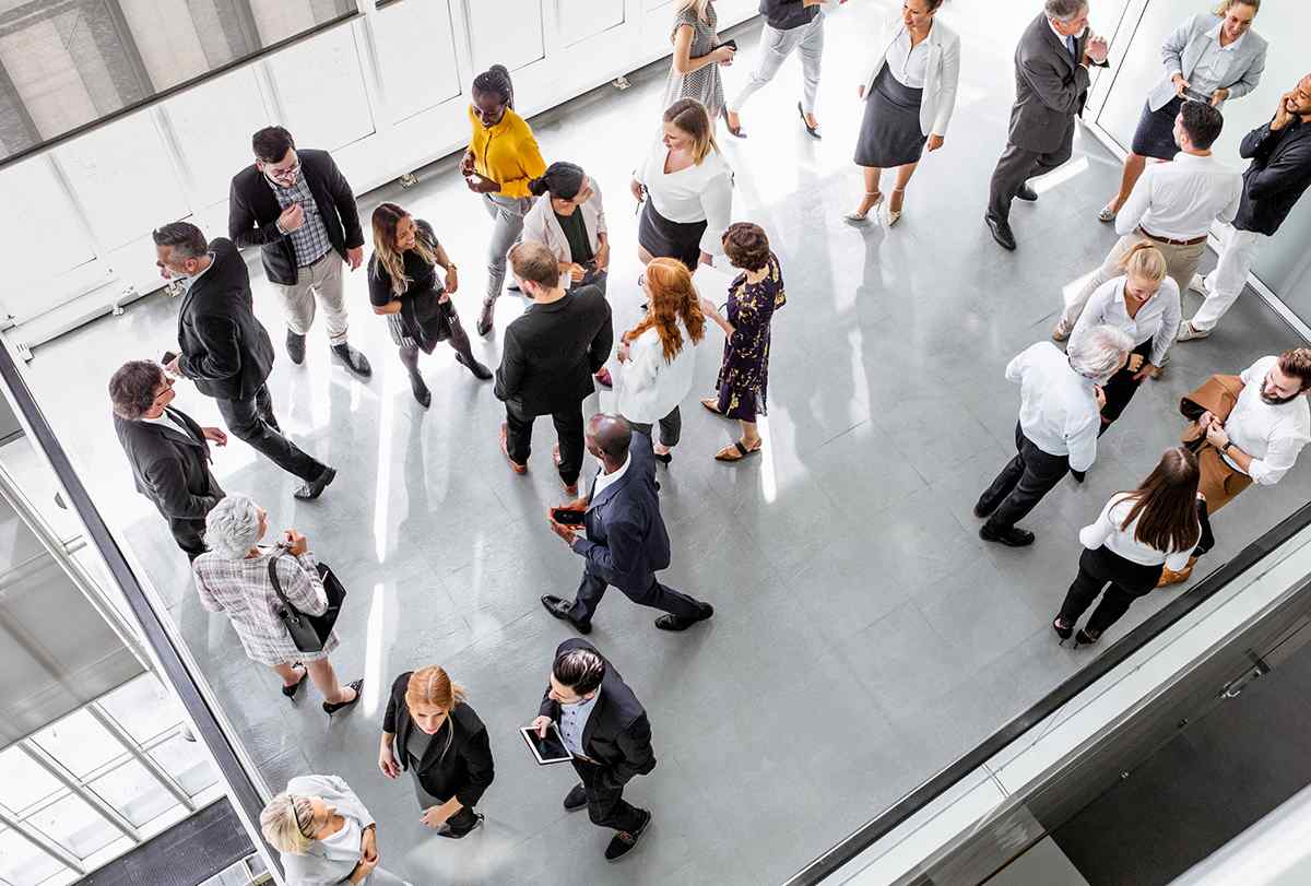 Top-down view of a company-wide gathering with business people mingling and chatting, symbolizing the importance of a targeted Ideal Customer Profile (ICP) for business owners and decision-makers