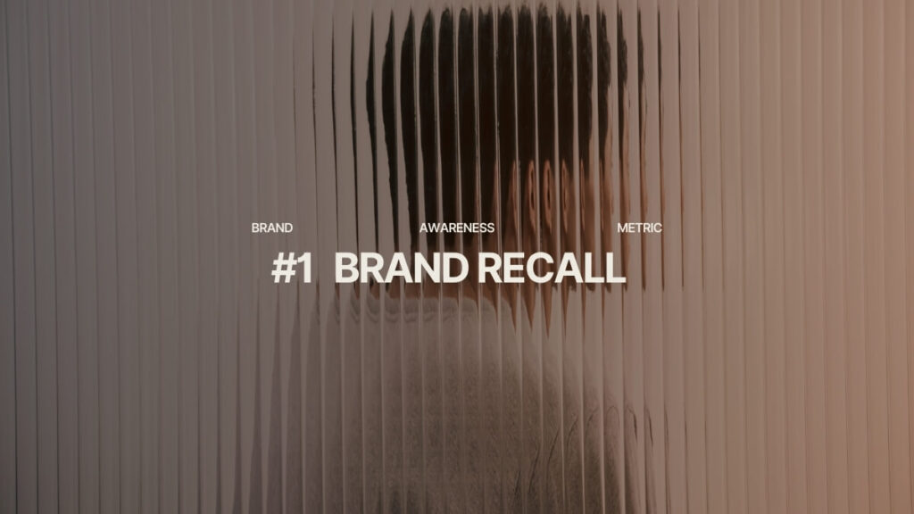 Blurred portrait behind vertical lines of Plexiglas, with "Brand Recall" text overlay. Brand Recall is one of the main brand awareness metrics kpi.