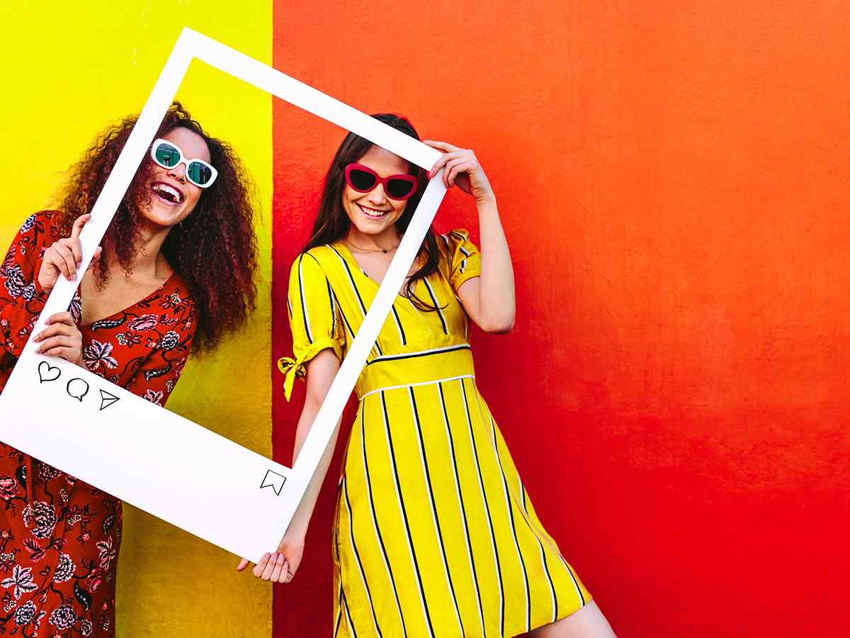 Two women posing with social media frame prop for brand awareness