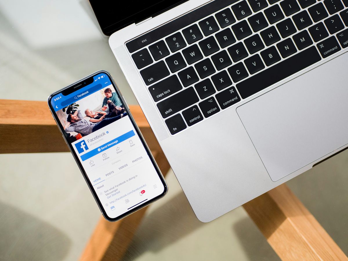 Smartphone displaying Facebook next to a laptop keyboard. A concept of digital product design journey.