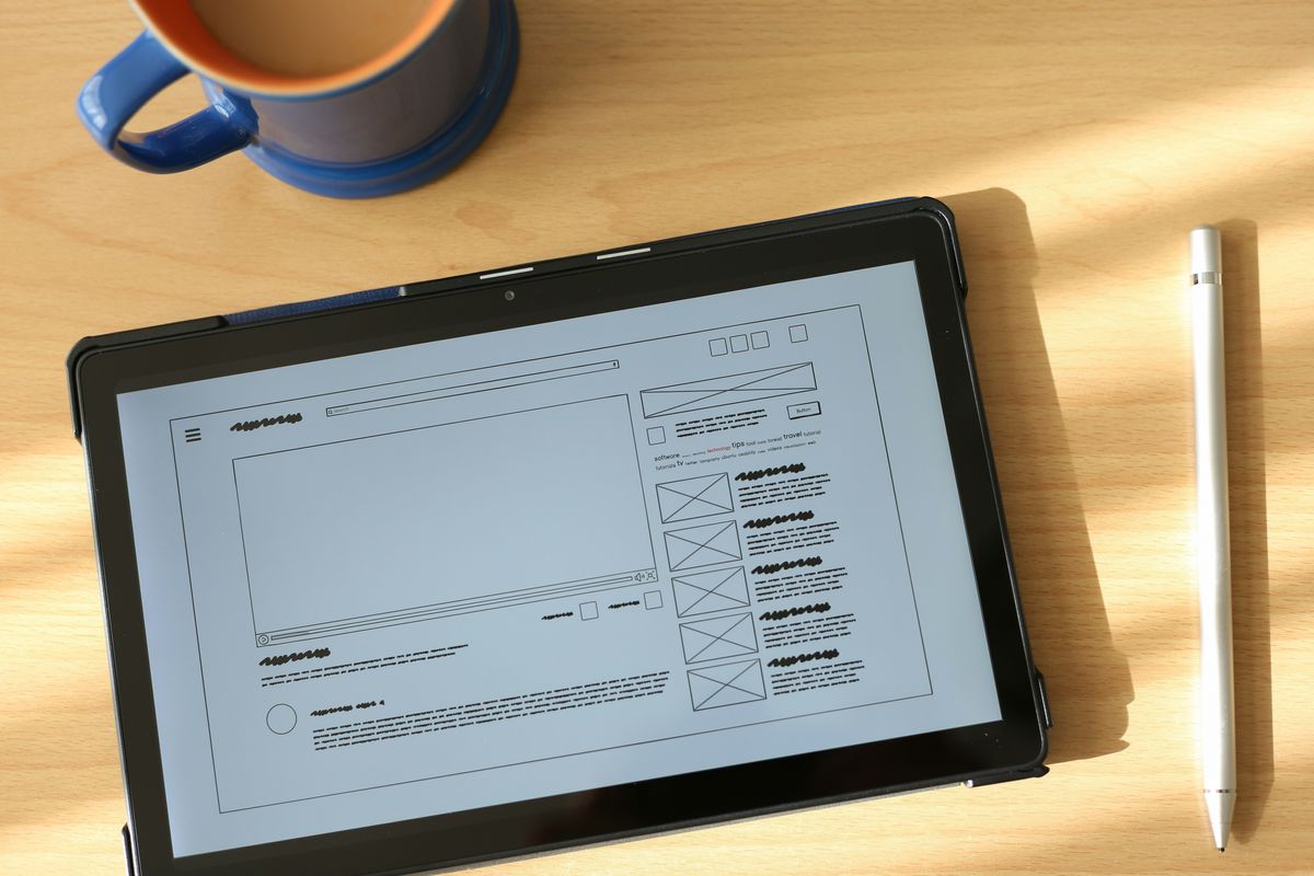 Tablet displaying a wireframe layout on a wooden desk.