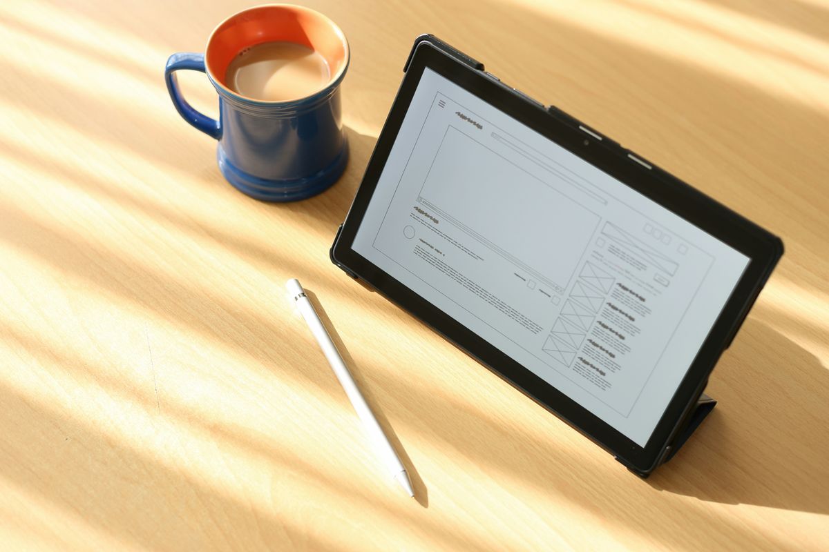 Tablet displaying a product design mockup next to a coffee mug.