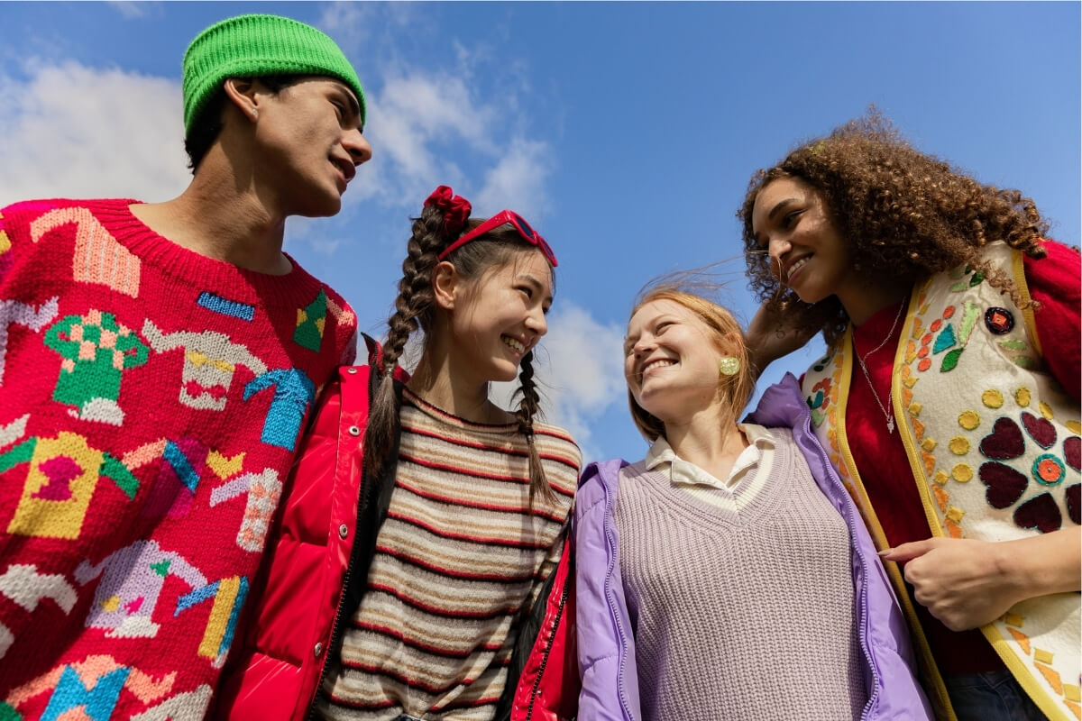 A diverse group of young people holding each other and smiling. Representing community-led growth in growth marketing.