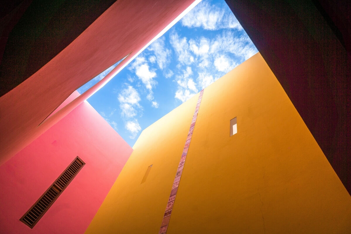 Colorful building with blue sky. Low angle shot, with massive walls surrounding the camera, and blue sky at the end. Concept image for overcoming SaaS growth challenges in growth marketing.